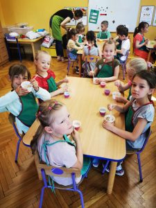 Dzieci wokół stołu w papilotkach wokół stołu sporządzają zdrową granolę