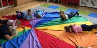 Dzieci leżą na kolorowej chuście animacyjnej