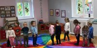Dzieci stoją na chuście animacyjnej, na kolorze czerwonym
