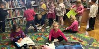 Grupa dzieci w bibliotece ogląda książki