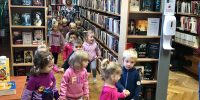 Grupa dzieci chodzi między regałami w bibliotece