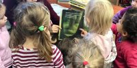 Bibliotekarka czyta bajkę, dzieci oglądają obrazki w książce