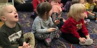 Dzieci, które siedzą na dywanie słuchają występu Pań z opery