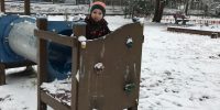 Chłopiec pozuje do zdjęcia na urządzeniu ogrodowym